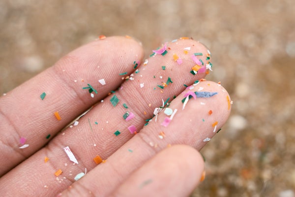 Gros plan latéral de microplastiques sur une main.