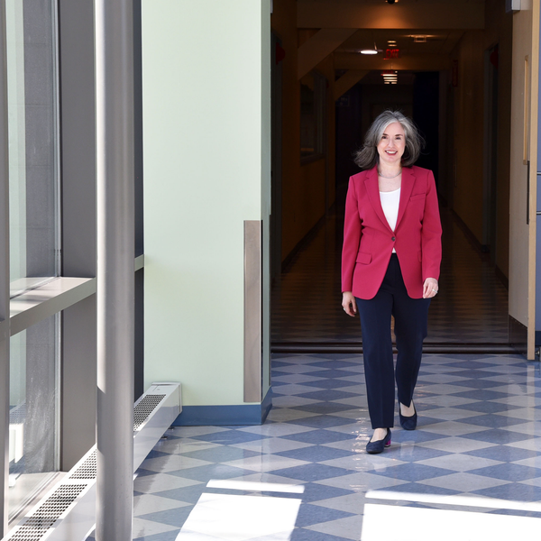 Jessica Kirshner walking toward the camera in a red blazer