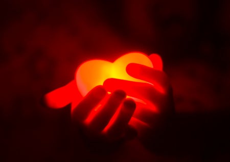 Hands holding a glowing heart