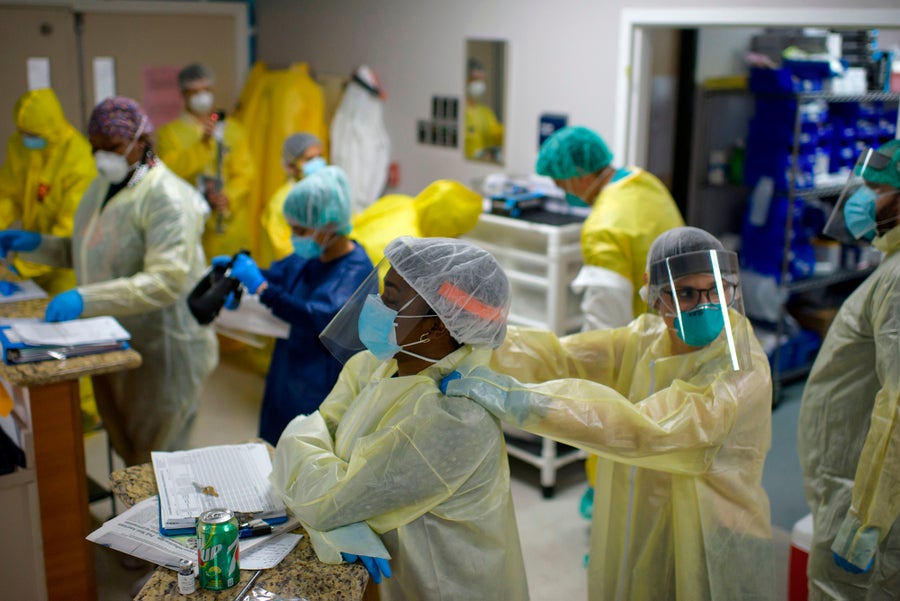 Healthcare workers in yellow PPE offering support to one another