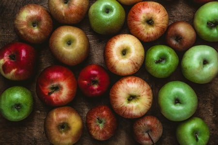 A variety of apples on a rustic wooden table