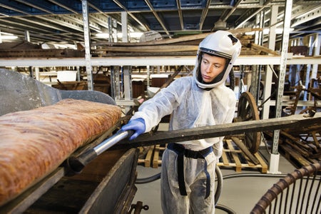A woman in a safety suit cleans objects in a storage facility