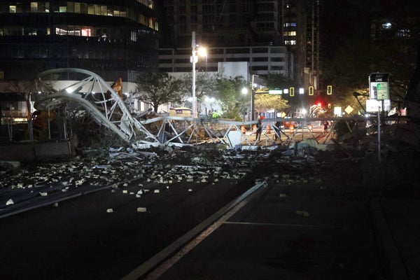 The crane crashed into a building and is sitting on the street.