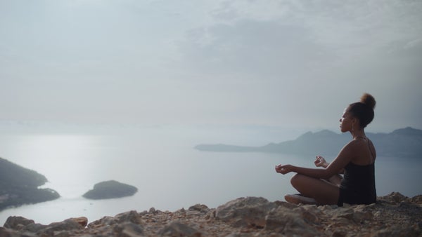 Woman meditating with ocean in the background.