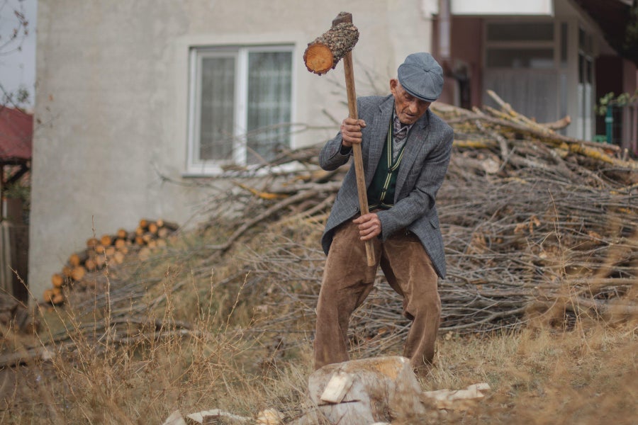 An elderly man chopping wood