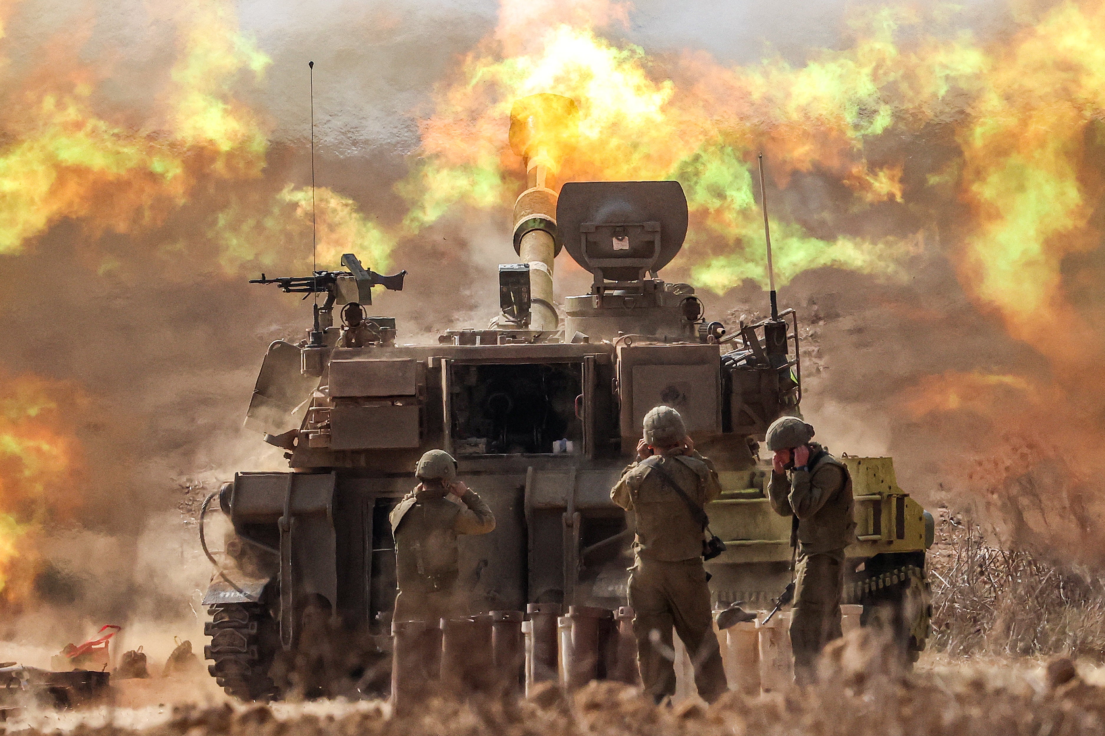 Three soldiers in front of an Israeli tank with inferno in background.