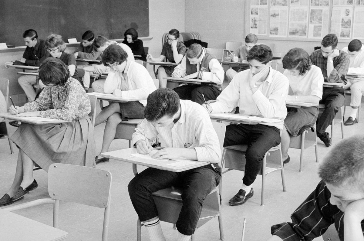 Black-and-white photograph of a room full of teenage students bent over their desks taking an exam.