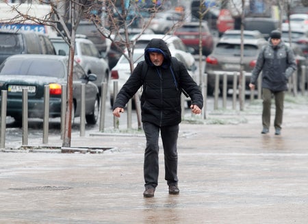 A man walking carefully on an icy sidewalk.