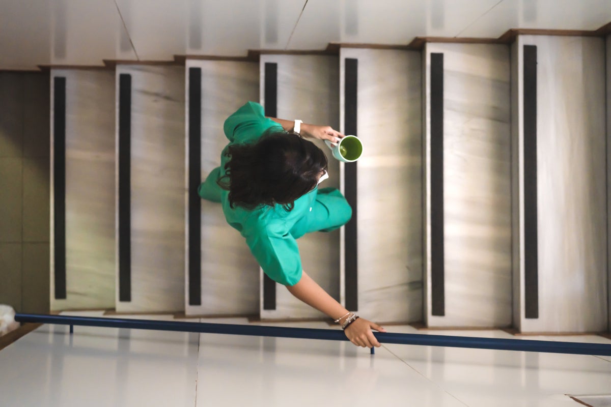 a woman in a nurse uniform holding a cup of coffee walks up stairs