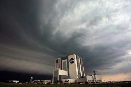 Wide angle photograph of the NASA Vehicle Assembly Building in Cape Canaveral, Florida with a thunderstorm looming overhead