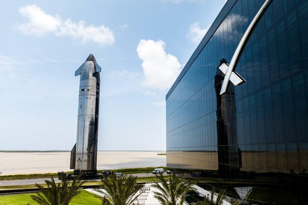 Rocket de prata maciço fica atrás do baixo edifício industrial no local