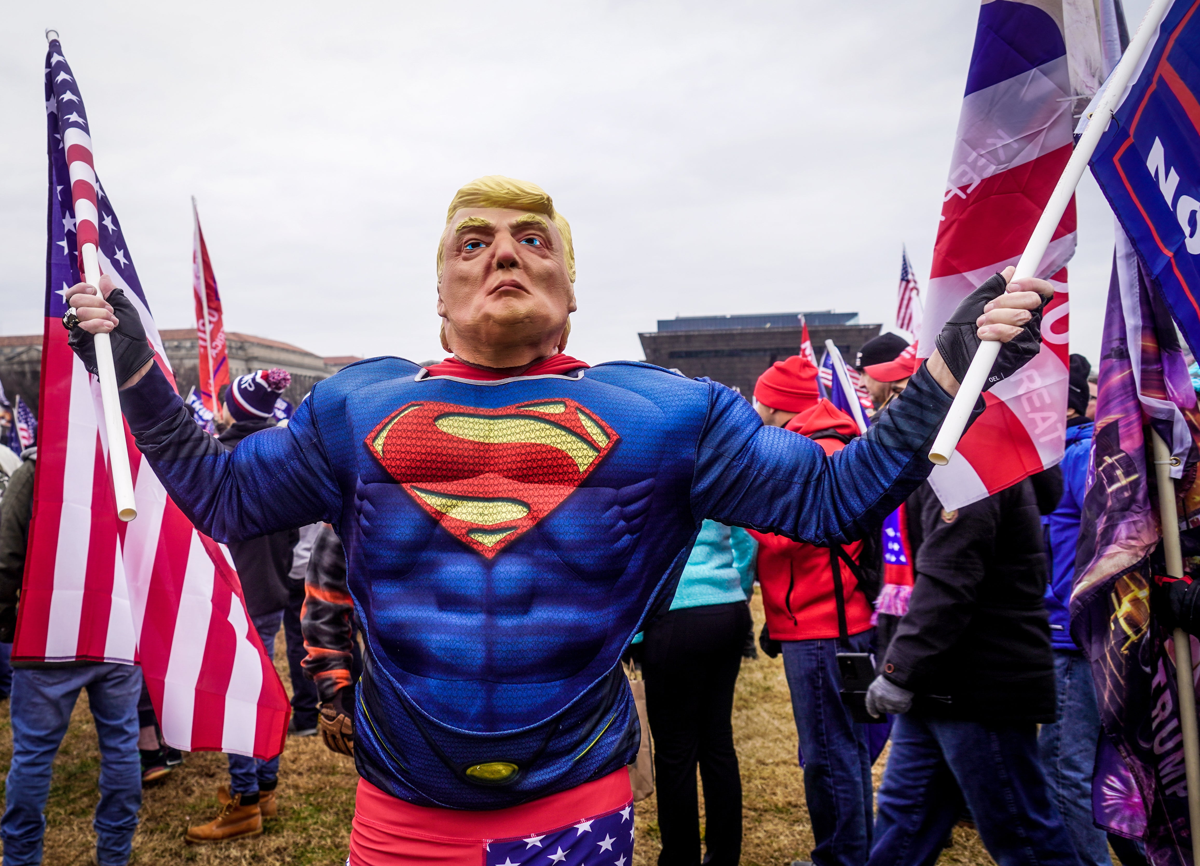 A Trump supporter dressed in a Superman costume holding an American flag at a Stop the Steal rally