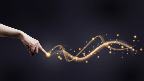 A human hand pointing its index finger at a glowing trail of waves against a dark background