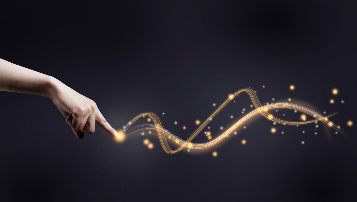 A human hand pointing its index finger at a glowing trail of waves against a dark background