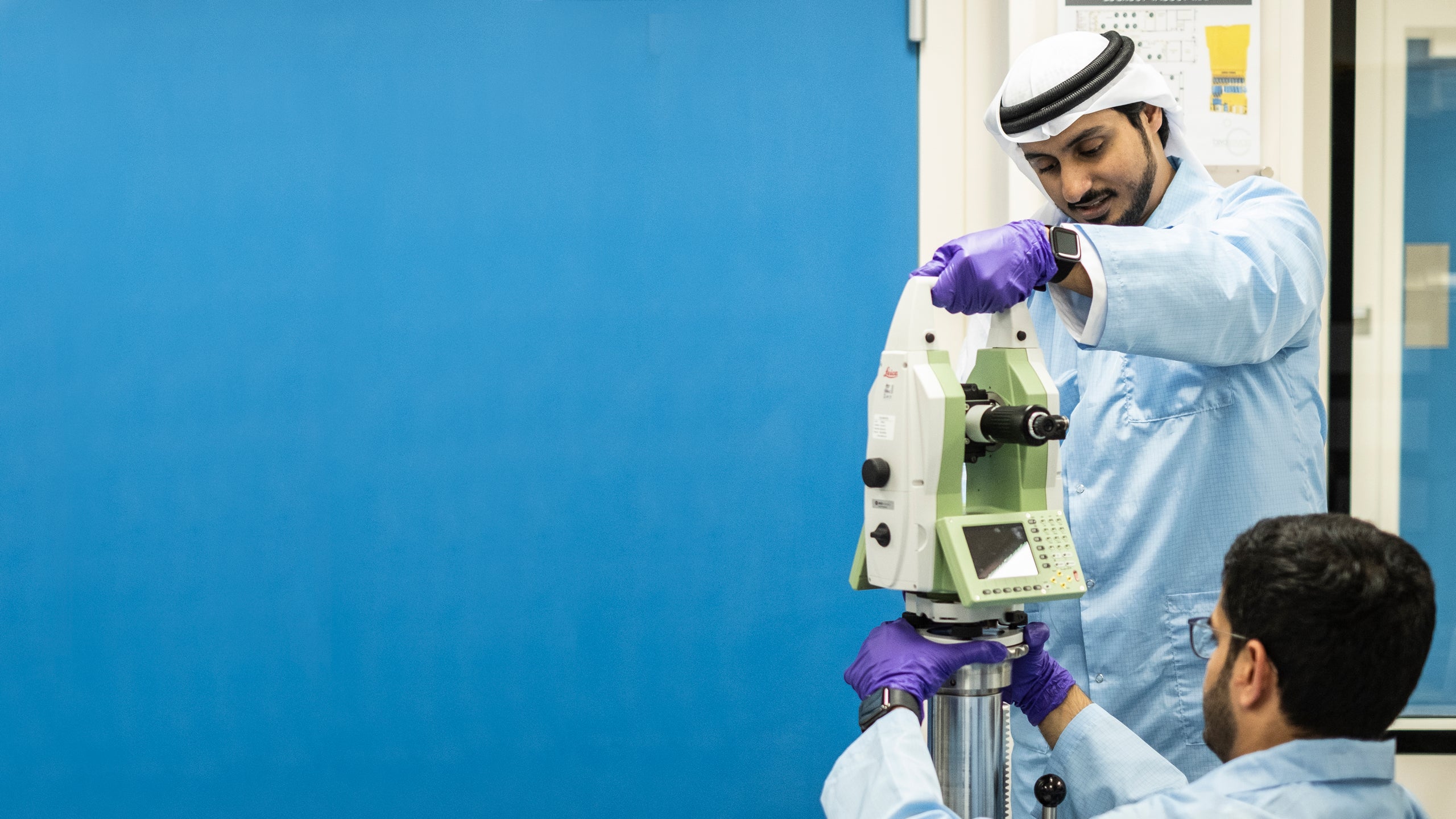 Muna al Hammadi watches Ali al Suwaidi and Mahmood Alawadhi adjust a measuring device in a lab