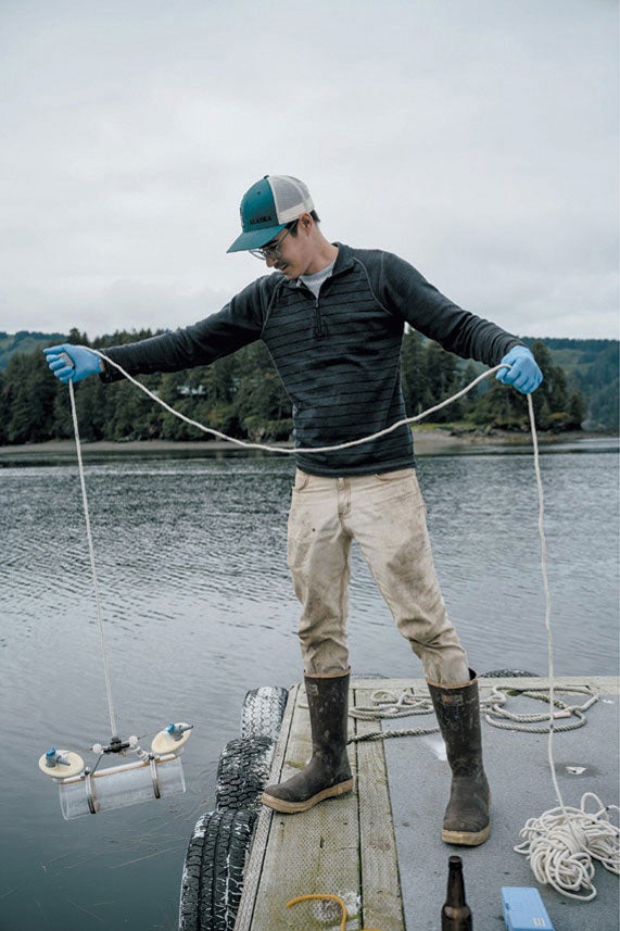 Environmental assistant collects samples of bay water.