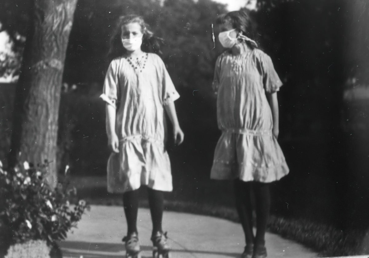Two people wear masks in this photograph from 1918–1919.