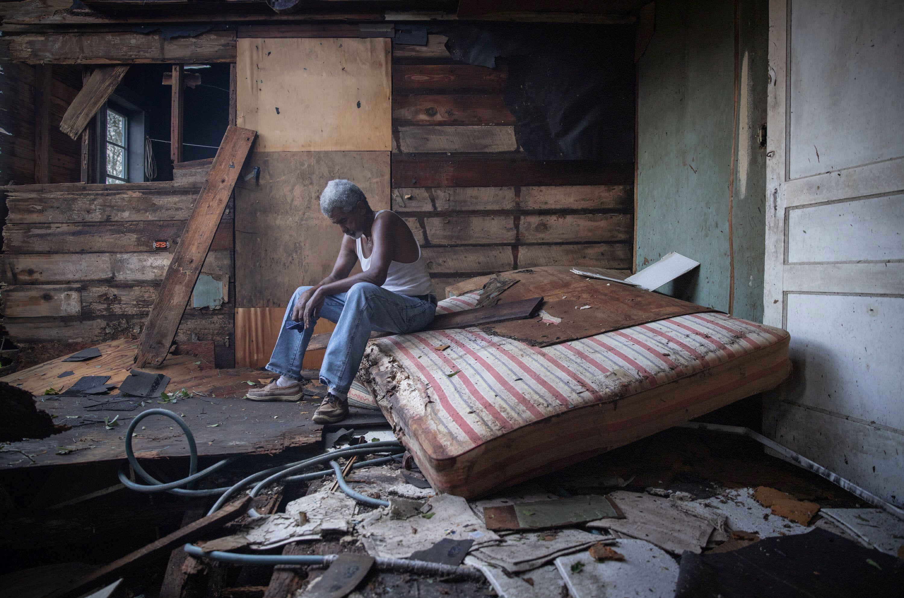A man sits inside his house which was heavily damaged by Hurricane Ida in Houma, Louisiana.