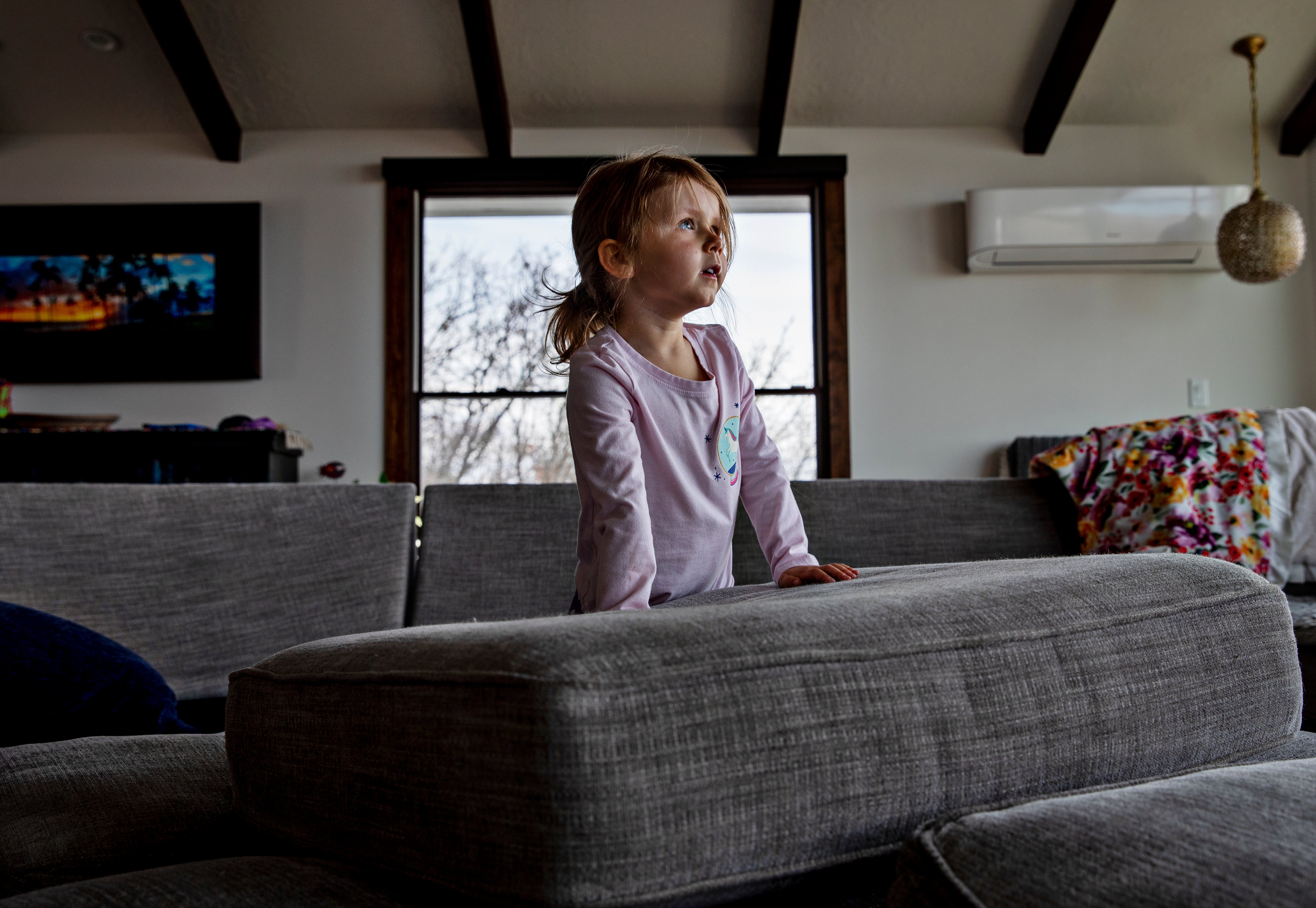 Four-year-old Evie Lewis in pink T-shirt is playing in her living room.