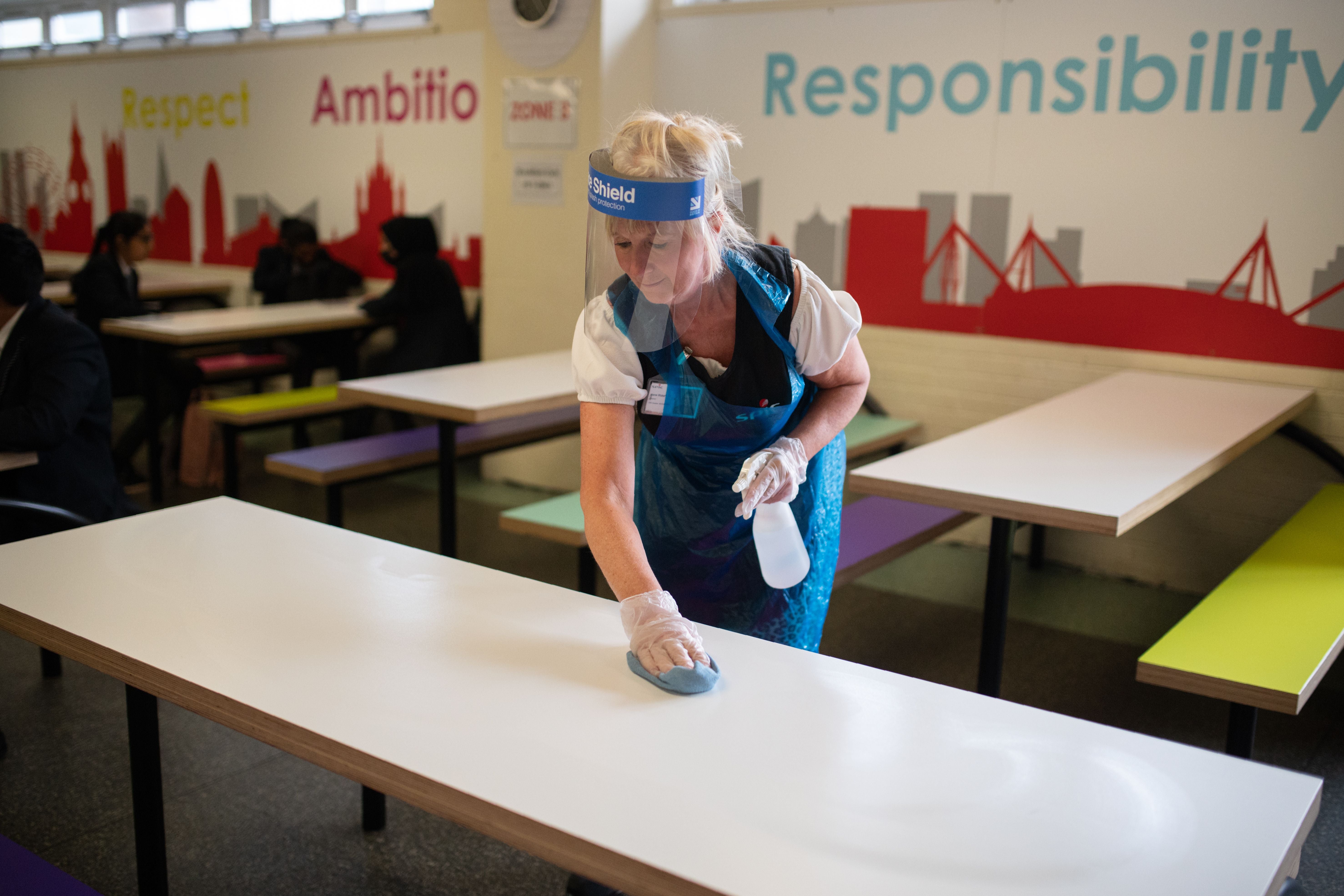 Woman cleaning school classroom table