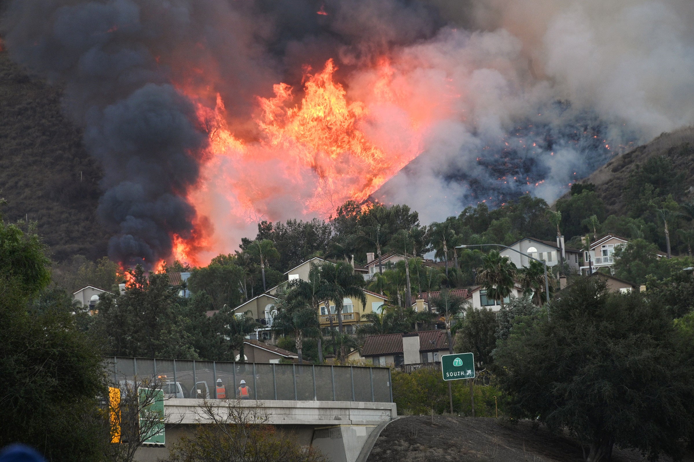 Flames are seen near homes off the 71 freeway at the Blue Ridge Fire in Chino, California, October 27, 2020