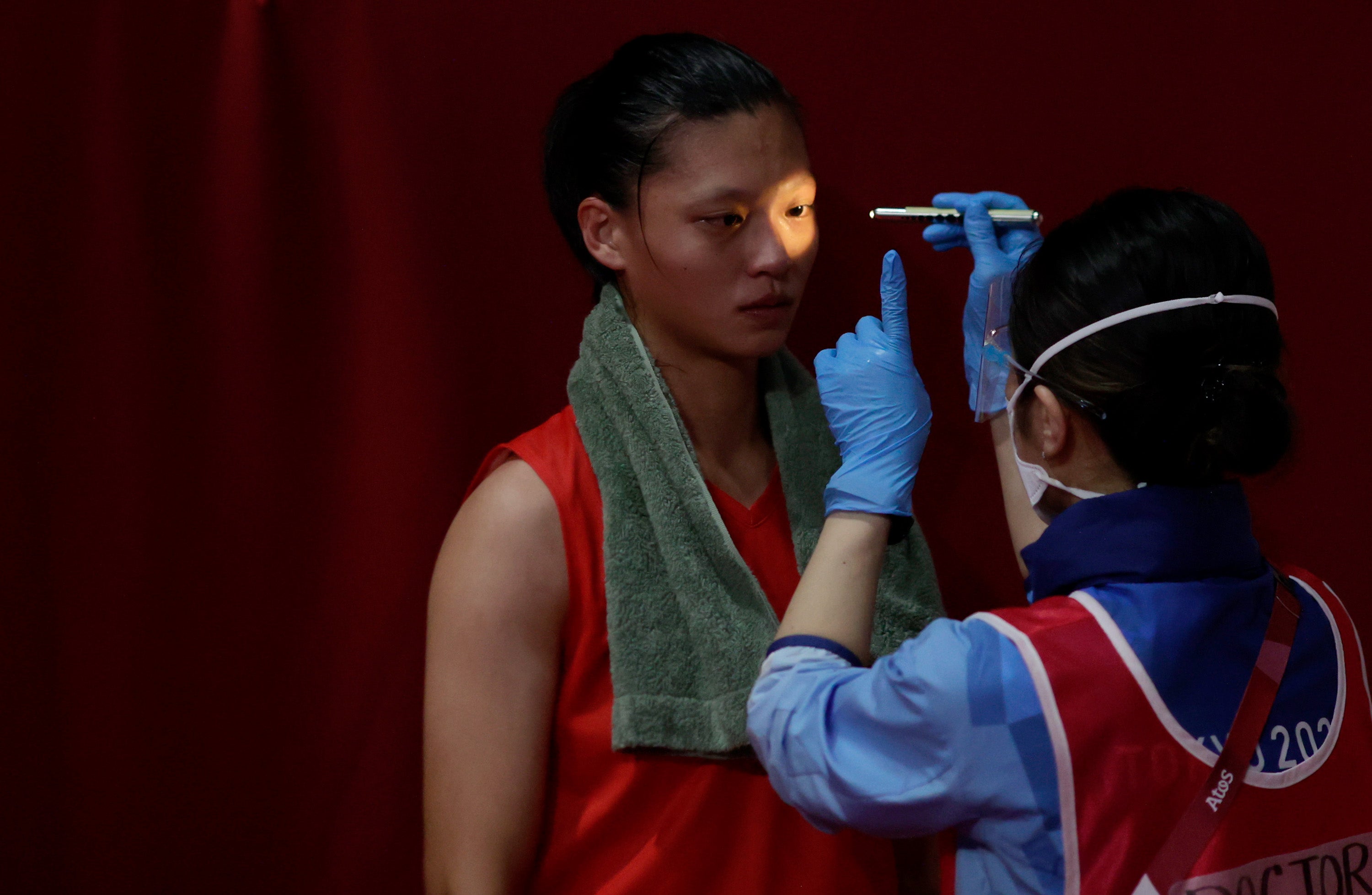 A doctor examines an athlete for injuries during a boxing match at the Tokyo Olympics in July 2021.