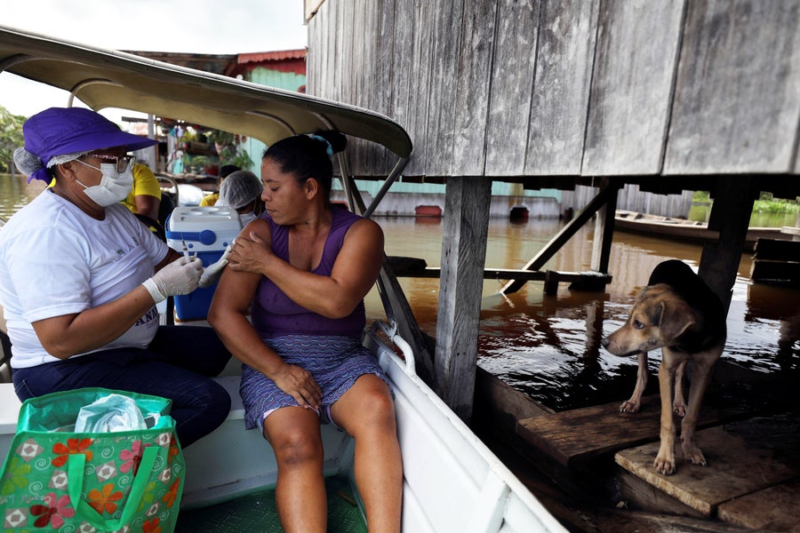 Health worker administers doses of the Oxford–AstraZeneca vaccine on a boat by the Amazon River in Brazil during a flood.