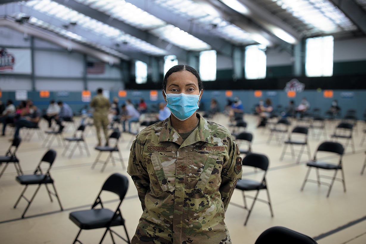 Physician and Air Force colonel Cecilia Sessions wearing military uniform and face mask stands inside vaccination site.