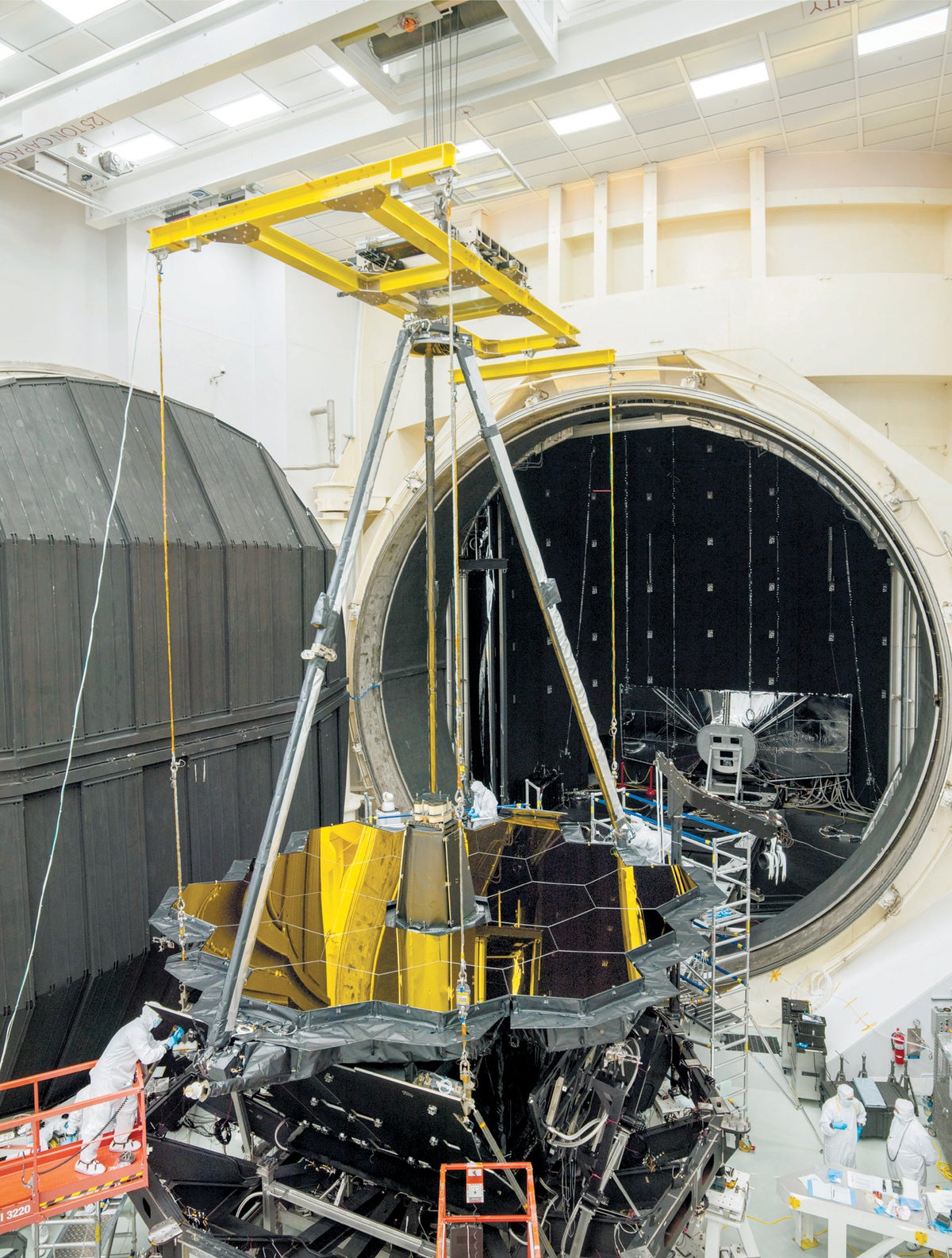 Workers preparing JWST parts for testing inside high-vacuum, cryogenic-optical test chamber.
