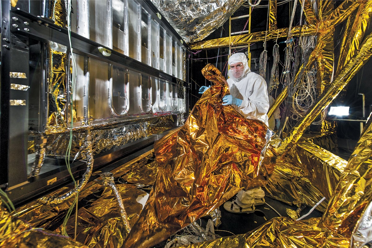 A technician carefully handles the gold foil used to enshroud instruments during cryogenic testing.
