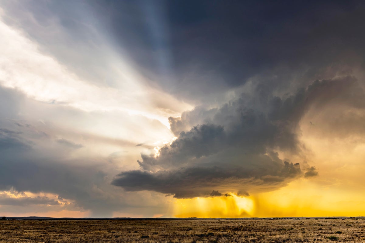 A tornadic supercell storm moving over the Great Plains during sunset.