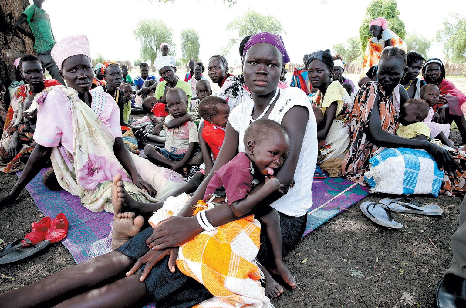 Large group of women and children sitting on the floor. 