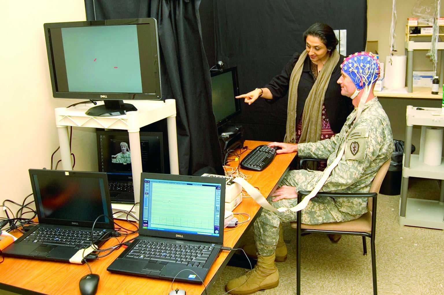 AMISHI P. JHA and Lieutenant General Walter Piatt review brain-wave recording procedures at a lab.