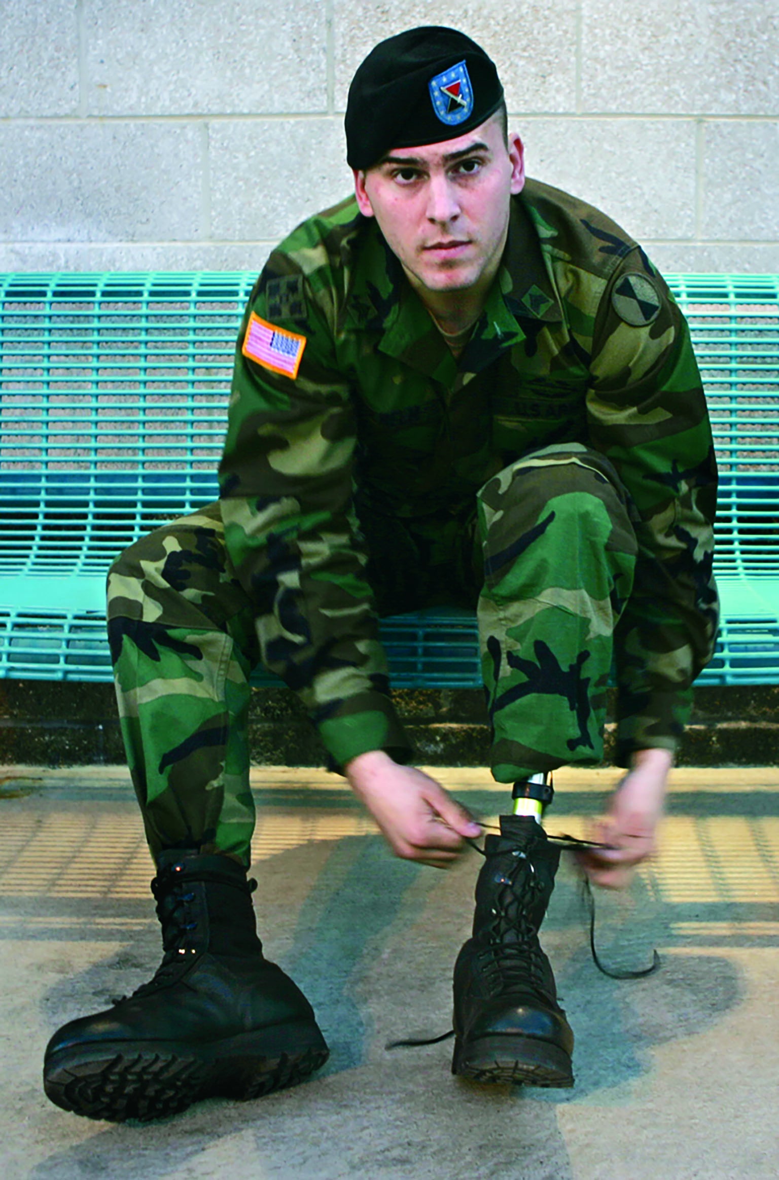Soldier tying up shoes of a prosthetic leg.