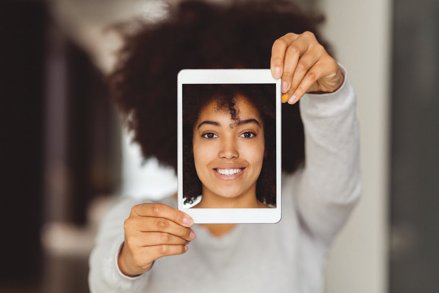 Woman holding up an identical picture of herself.