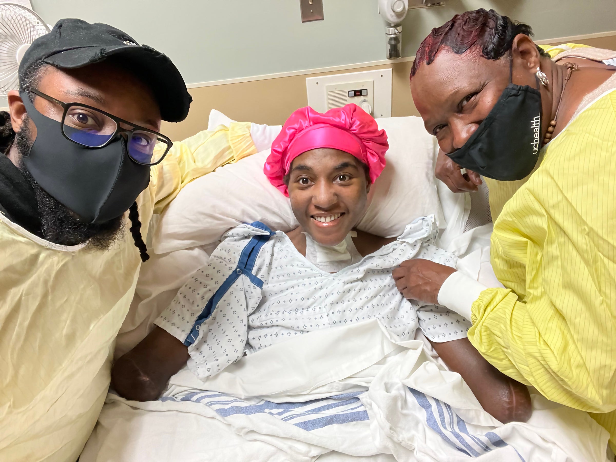 Candice in a hospital bed with brother Starr and mother Paige on each side.