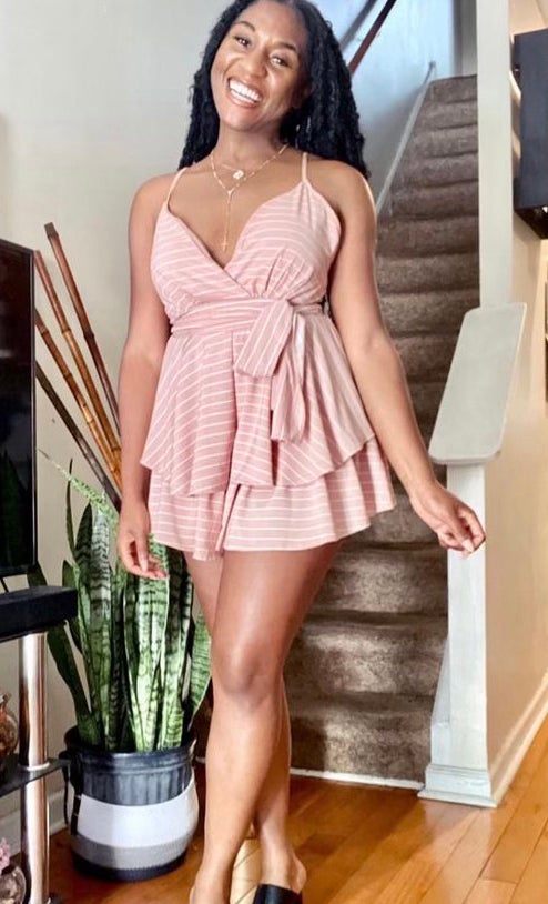 Candice Davis wearing a pink dress smiling and standing in front of a staircase.