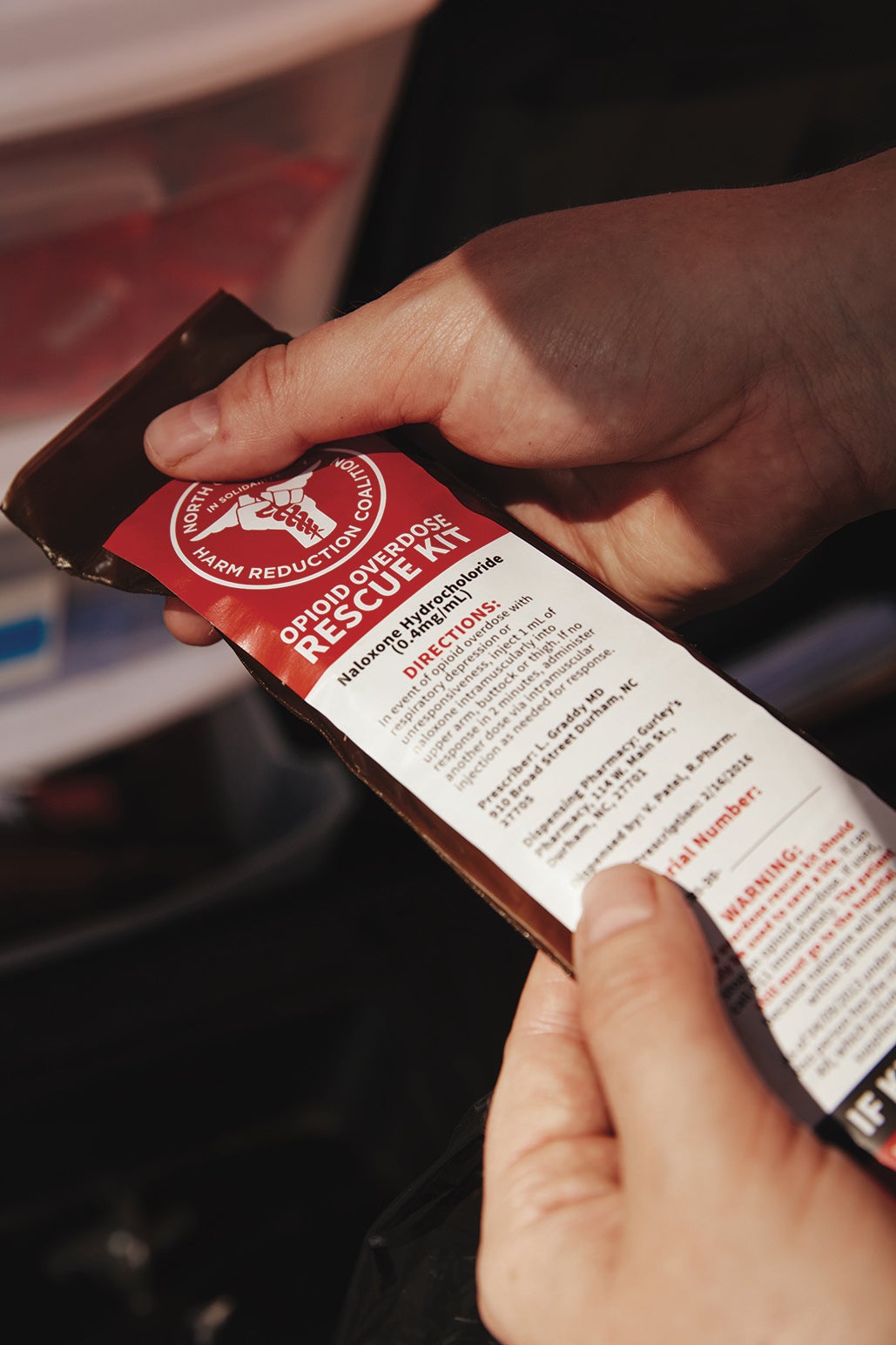 Hand holding an opioid overdose rescue kit.