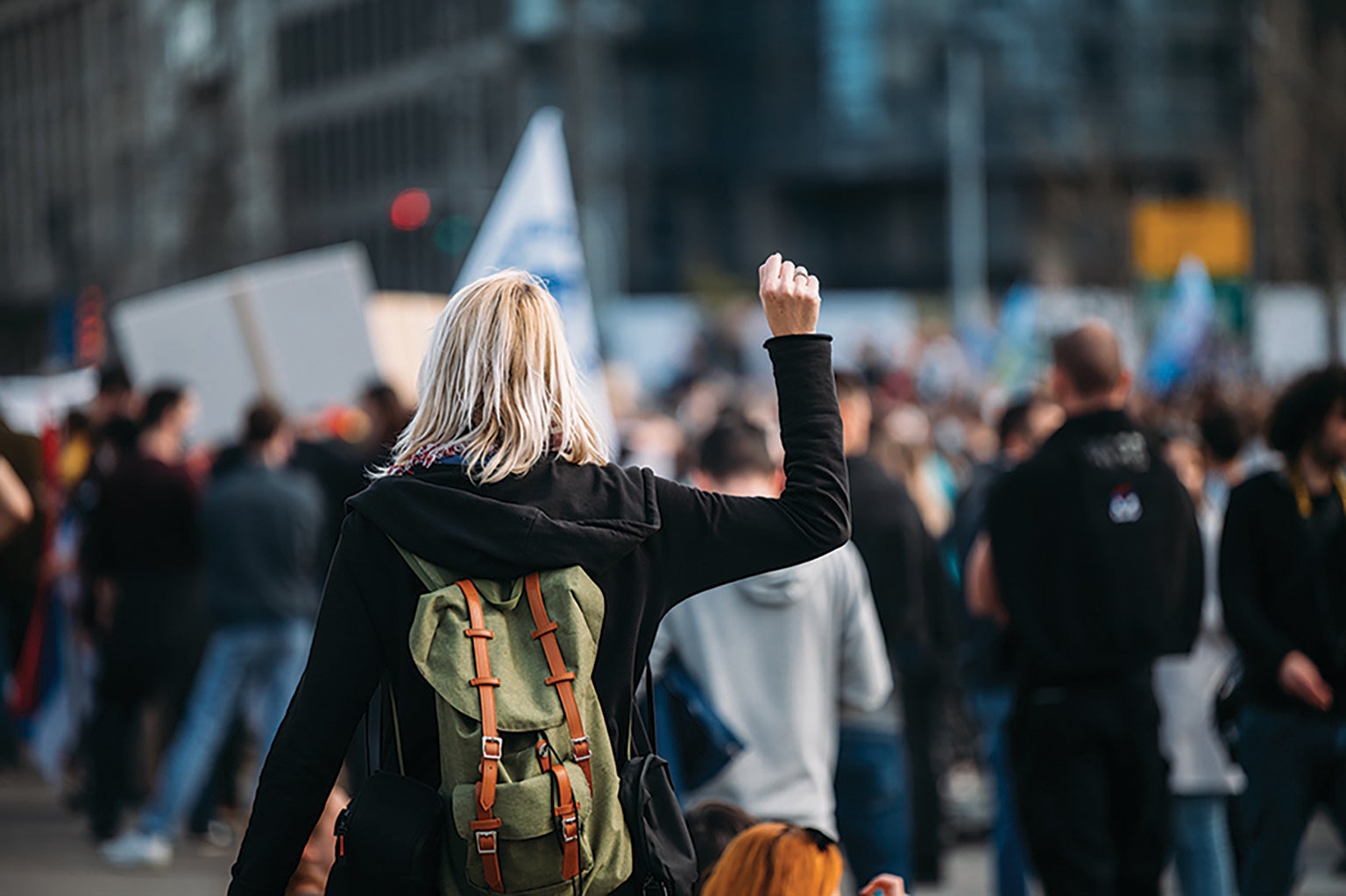 Woman walking toward a crowd with her right fist raised.