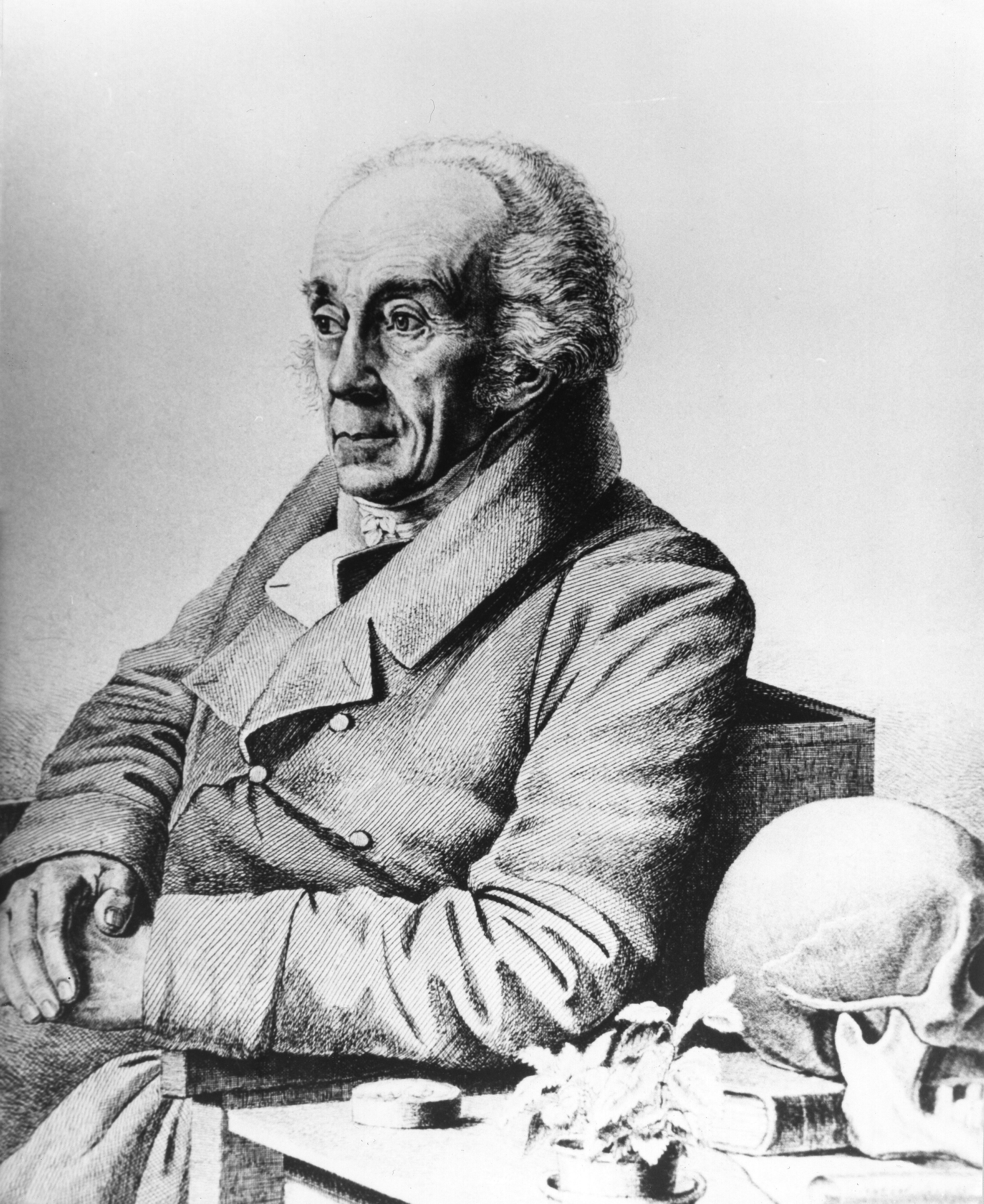Anthropologist Johann Friedrich Blumenbach sitting at a table next to a skull.