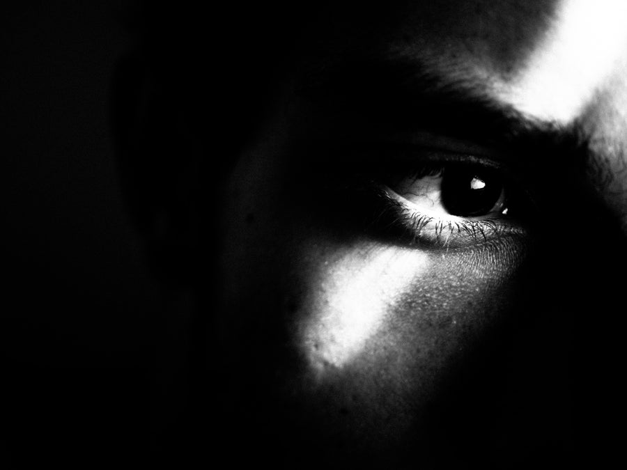 Black and white photograph, close-up of a man's eye illuminated in a beam of light