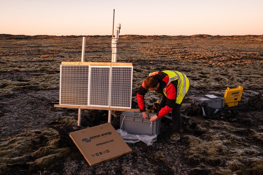 A person sets up a seismograph in a rugged terrain