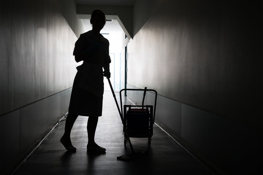 Silhouette of a woman mopping the floor in a dark hallway