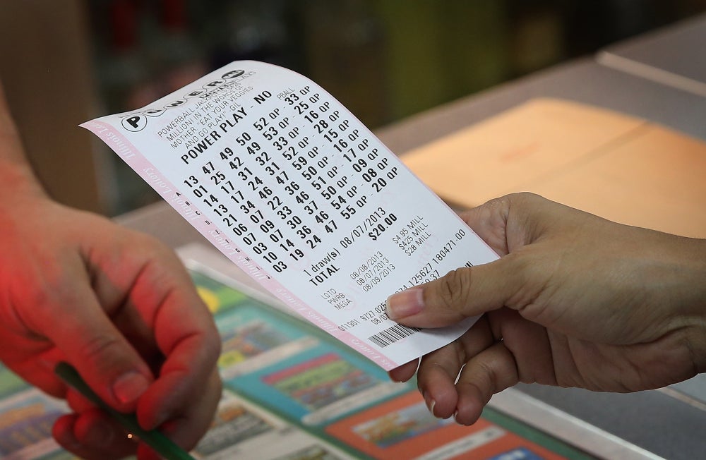 A customer is handed the Powerball ticket they purchased from a cashier at the counter inside a 7-11 store
