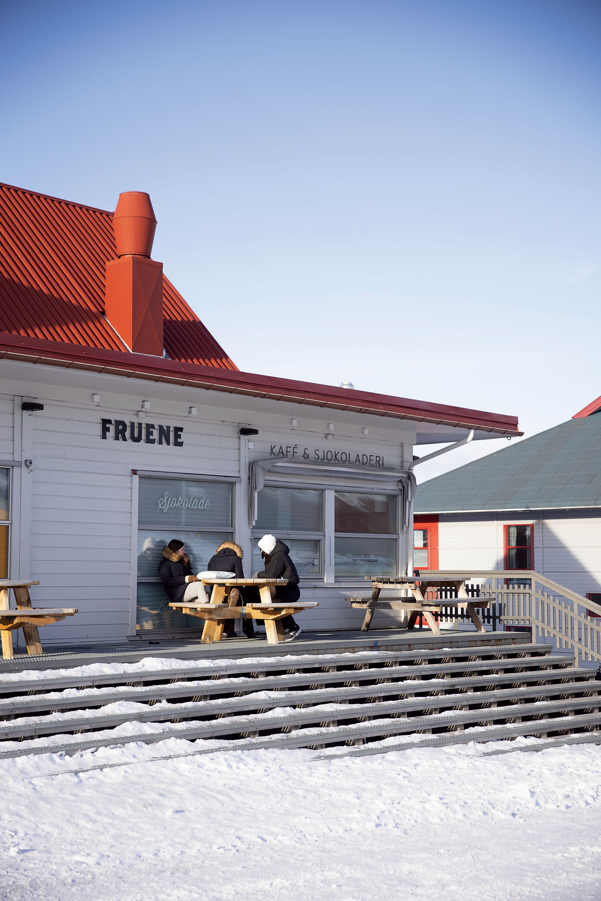 Three people wearing coats sitting outside of the Fruene cafe.