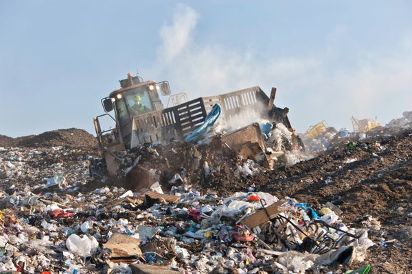 A bulldozer plows across a landfill.