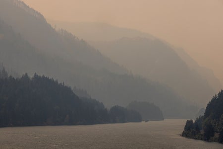 Hazy skies hang over a river with mountains seen in the background