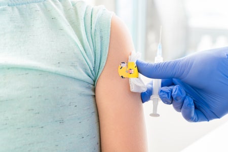 Little girl with colorful band-aid on arm.