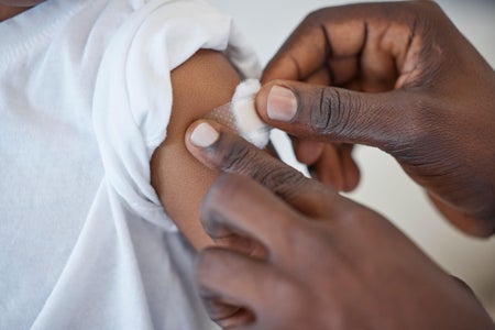 Medical professional applies bandage to arm of young child in health care office