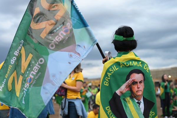 Person draped in flag and holding flag in support of Jair Bolsonaro
